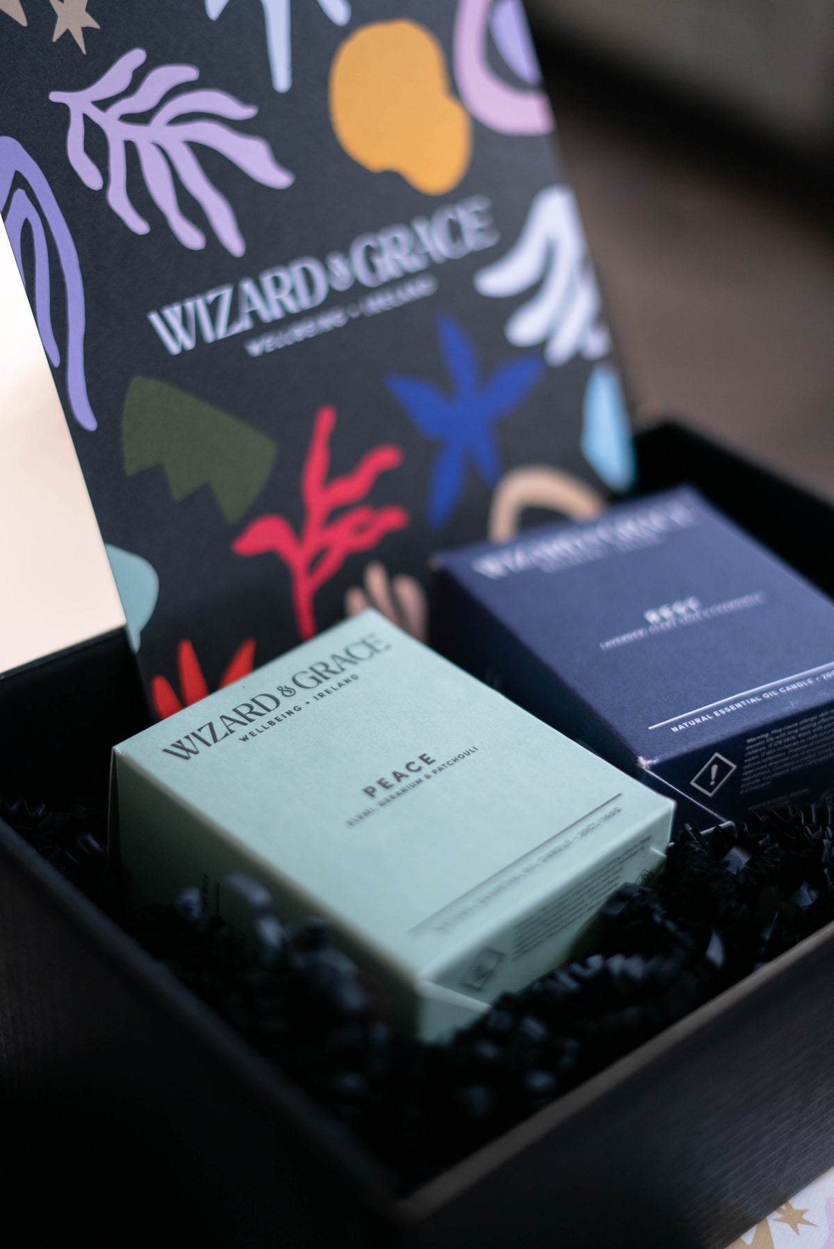 A close-up of a box containing two Wizard & Grace candles